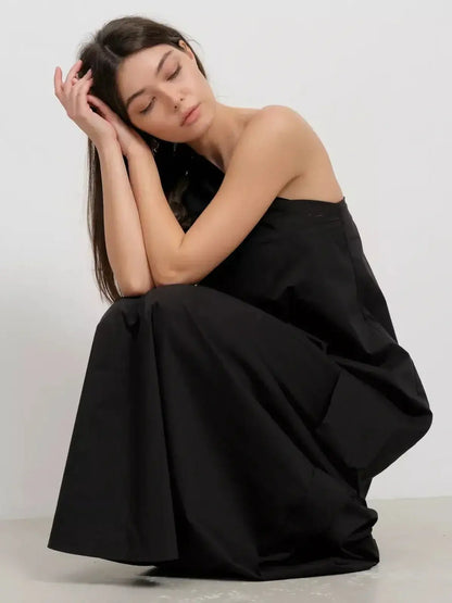 Model in a black one-shoulder maxi dress, showcasing draped elegance and modern sophistication.