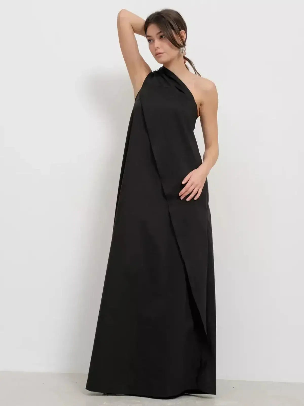 Elegant model wearing the Noir Fold Maxi Dress, showcasing a one-shoulder design and structured drape in classic black.