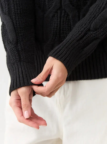Close-up of hands adjusting sleeve on Noir Knitwear by Lauven, a women's wool-blend turtleneck sweater.
