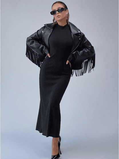 Woman in a sleek Noir Sculpt Maxi Dress with a trendy fringed leather jacket and sunglasses, exuding modern elegance.
