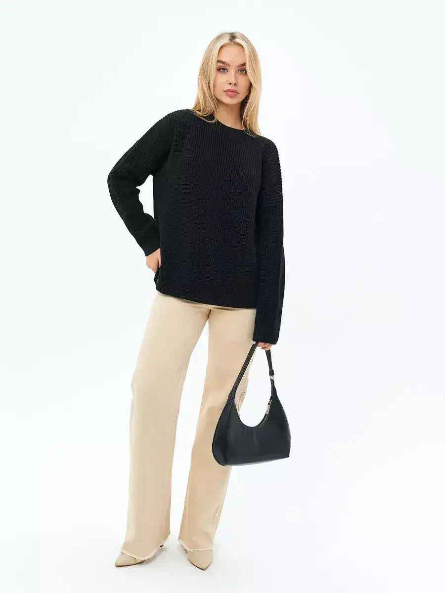 Model wearing the Noir Sweater by Lauven, an elegant oversized knit in classic black with chic beige pants.