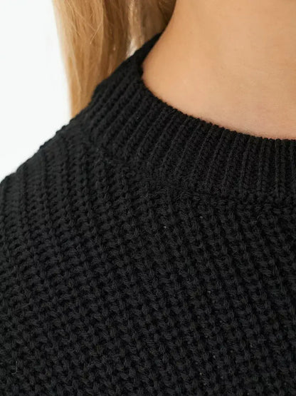 Close-up of the neck detail of the Noir Sweater by Lauven, showcasing its elegant oversized knit in classic black.