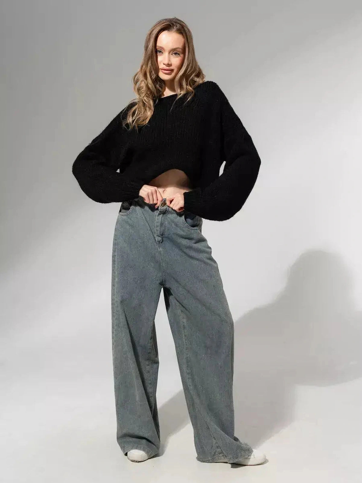 A model wearing the Noir Sweater by Lauven, showcasing an oversized off-shoulder knit in classic black.