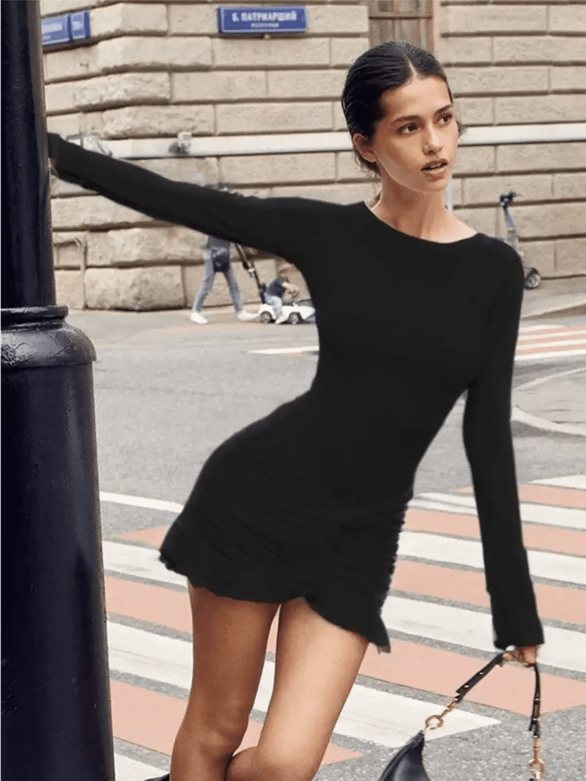 Model in a stylish black mini dress with long sleeves, perfect for cocktail parties or summer events.