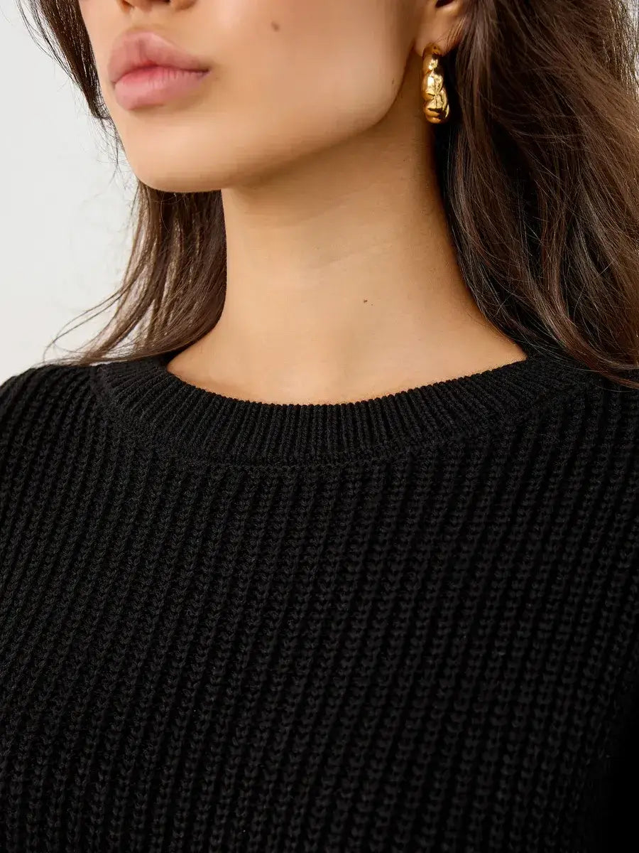 Close-up of a model wearing the Nola Sweater by Lauven, showcasing the oversized black knit and crew neck design.