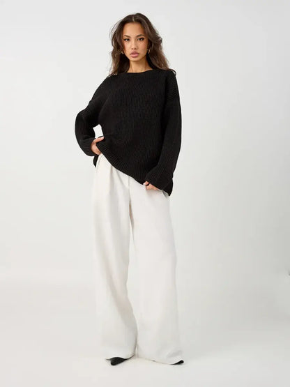Nola Sweater by Lauven, oversized black knit with crew neck, styled with white wide-leg pants.