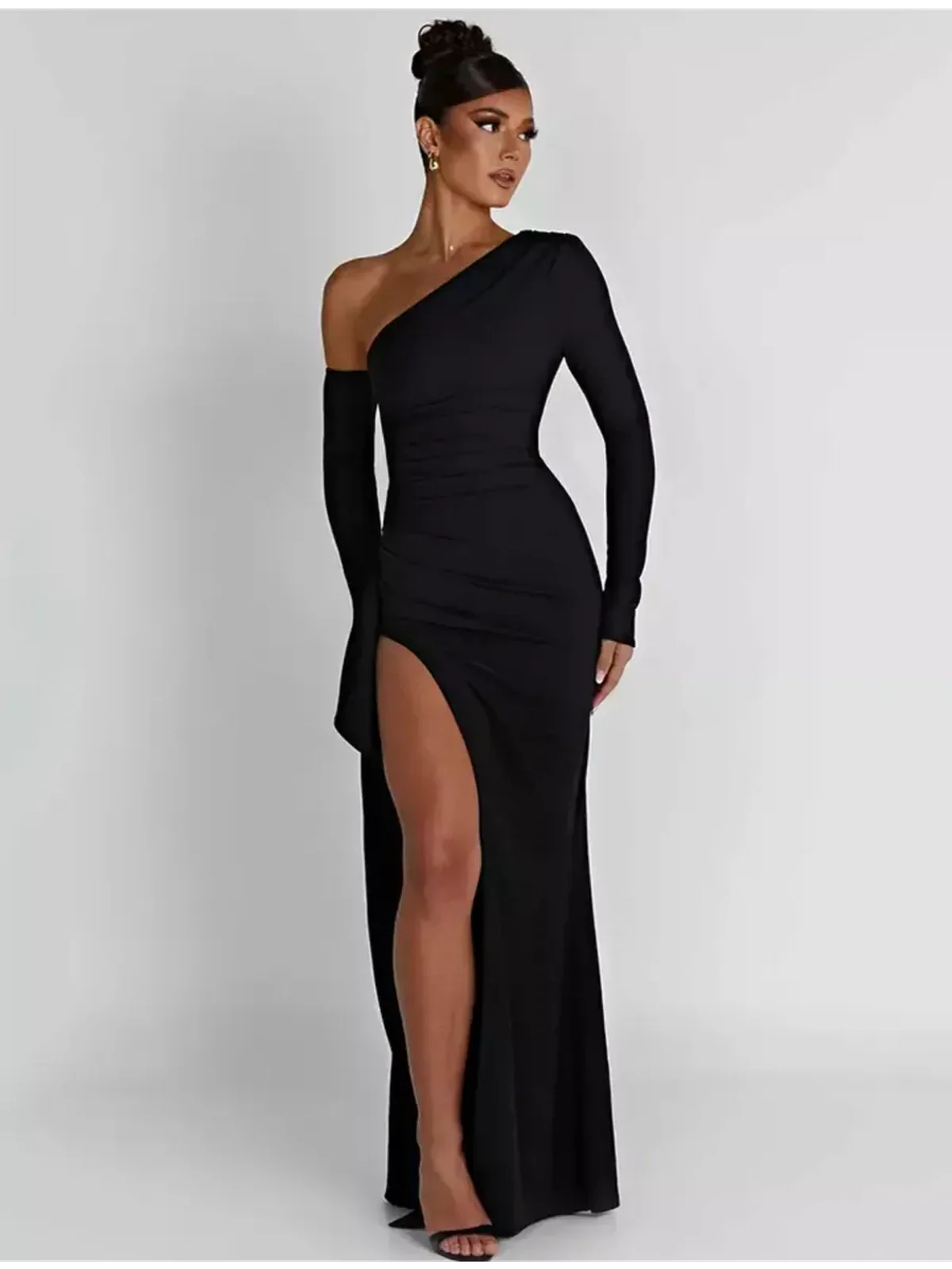 Elegant woman in black Obsidian Grace Maxi Dress featuring asymmetric design and thigh-high slit.