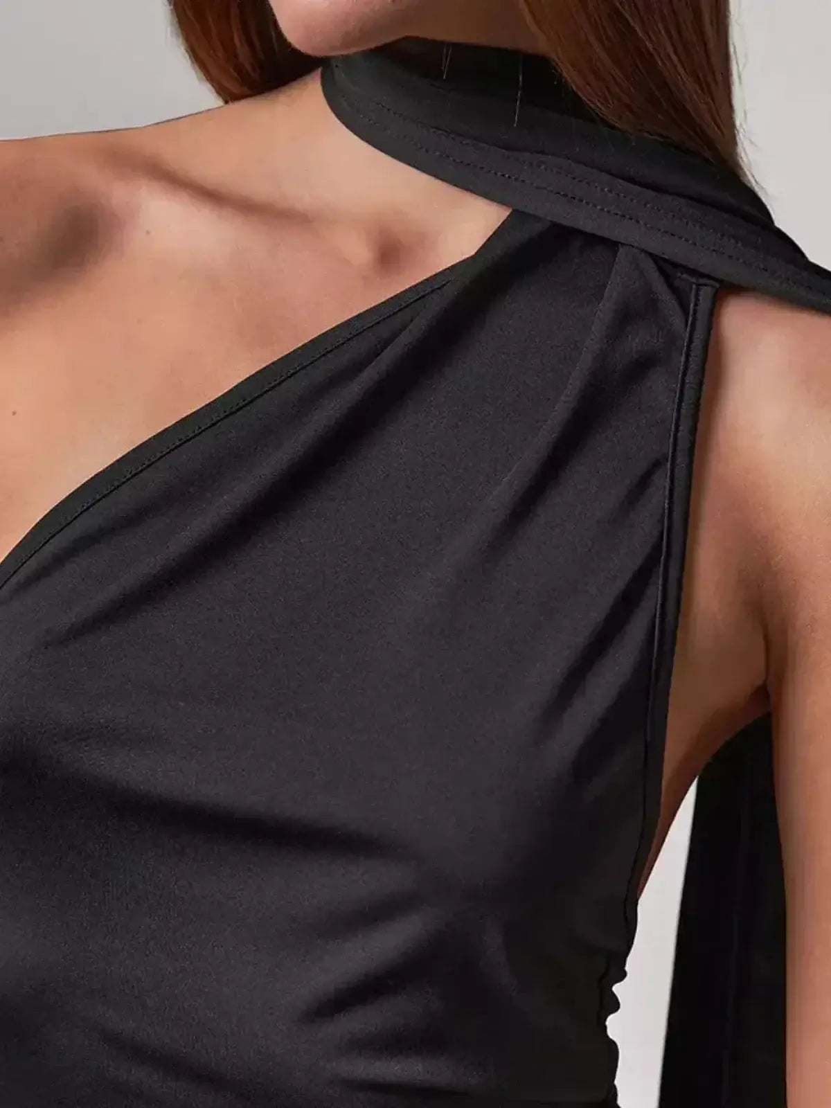 Close-up of the Obsidian Maxi Dress showcasing asymmetrical neckline and elegant scarf drape in sleek black fabric.