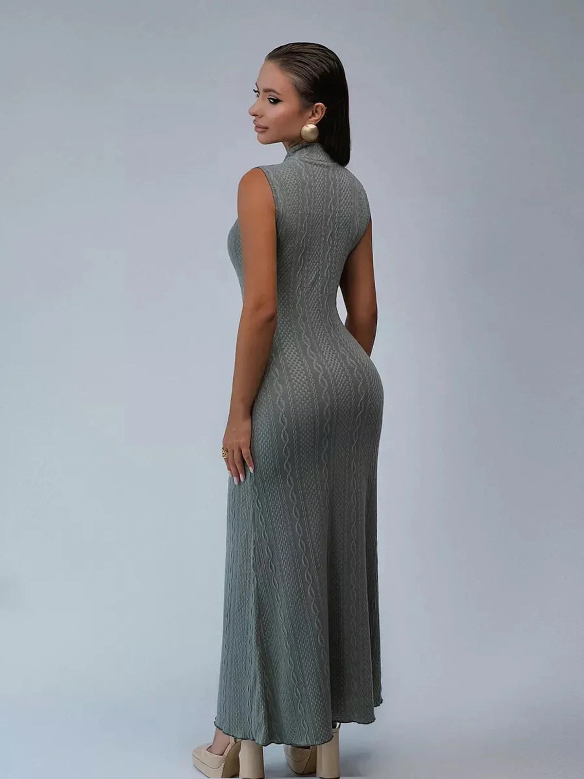 Woman wearing an elegant sleeveless Obsidian Veil Maxi Dress showcasing a cable-inspired texture from the back.