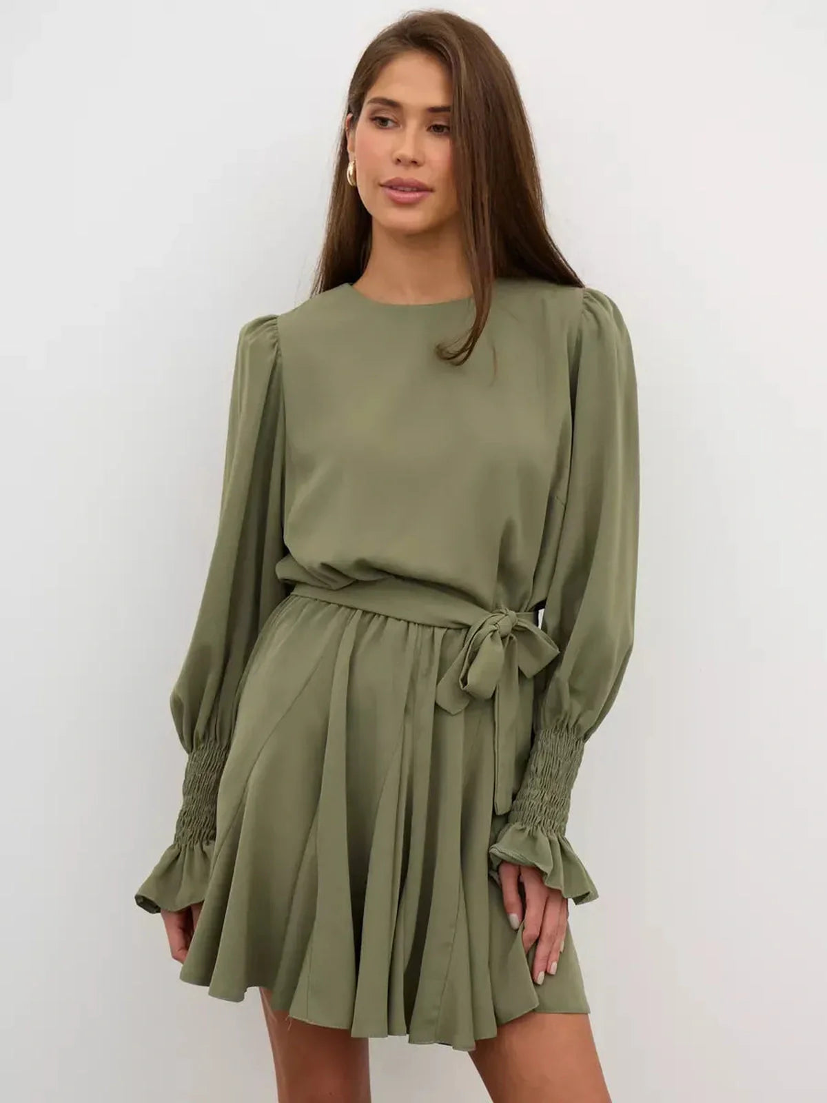 Model wearing Olive Luxe Mini Dress in sophisticated olive green with long sleeves and ruffle detailing.