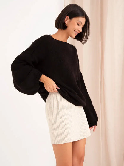 Stylish woman wearing the Onyx Sweater by Lauven, an oversized black knit sweater with a boat neck.