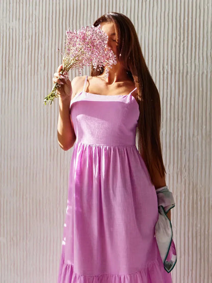 Model wearing a pink Petal Drift Maxi Dress, holding flowers, exuding summer elegance and a bohemian vibe.
