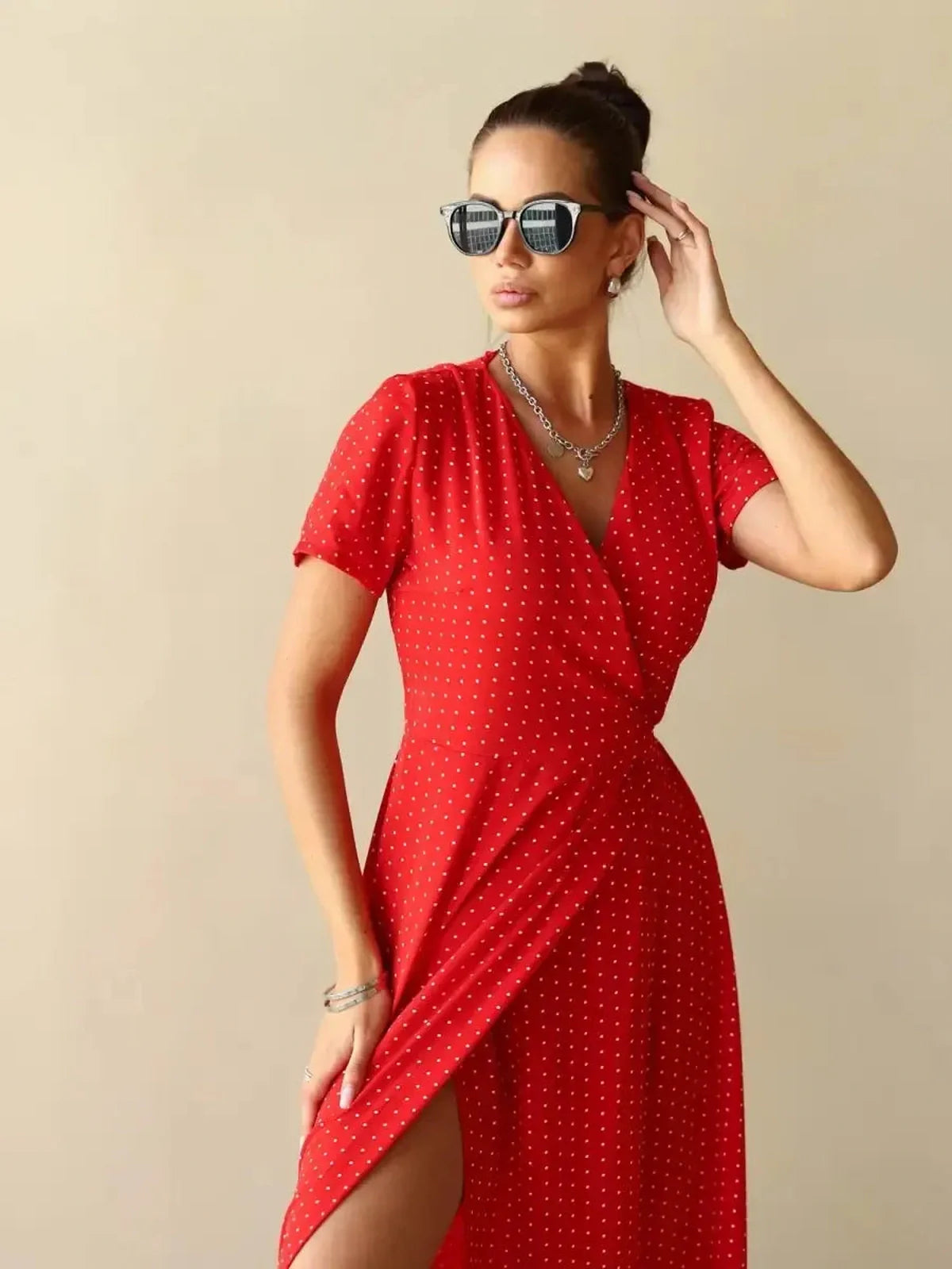 Model showcasing the Ruby Grace Maxi Dress in vibrant red polka dots, featuring a V-neckline and stylish sunglasses.