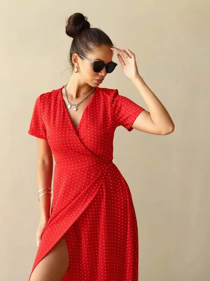 Woman in a red polka dot Ruby Grace Maxi Dress, showcasing a V-neckline and stylish side slit.