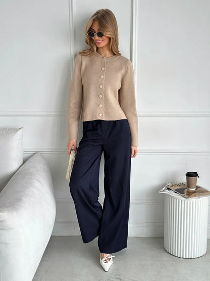 Sable Cardigan by Lauven, elegant cropped knitwear in beige, styled with navy pants and sunglasses.