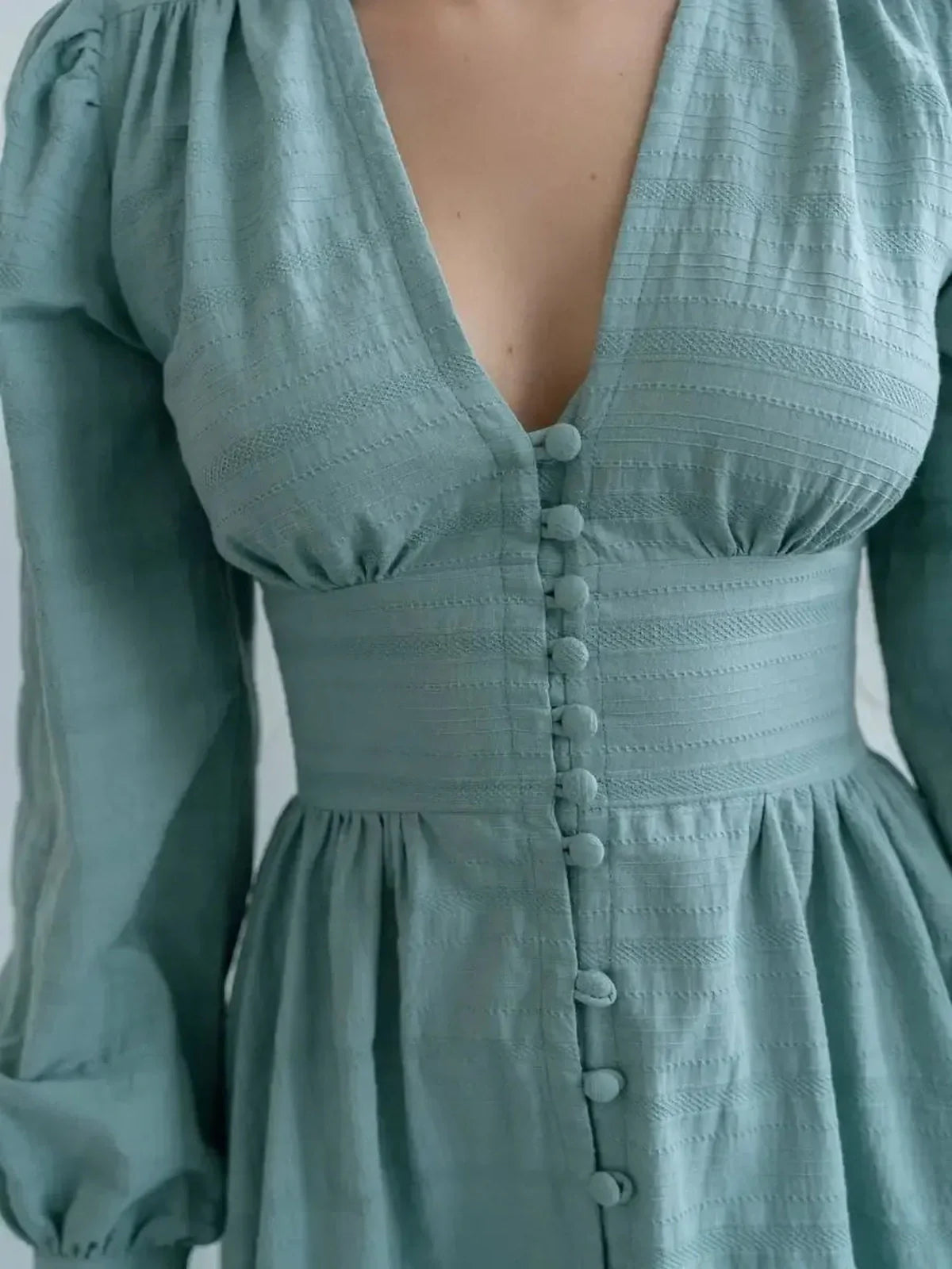 Close-up of the Sage Muse Maxi Dress, featuring a deep V-neck, textured fabric, and elegant fabric-covered buttons.