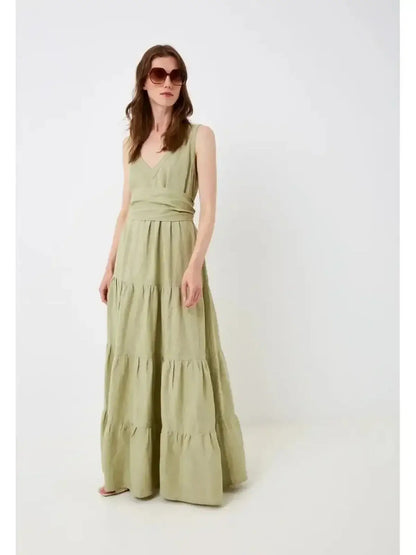 Model wearing Sage Whisper Maxi Dress in olive, featuring linen fabric, V-neckline, and gathered tiers for summer elegance.