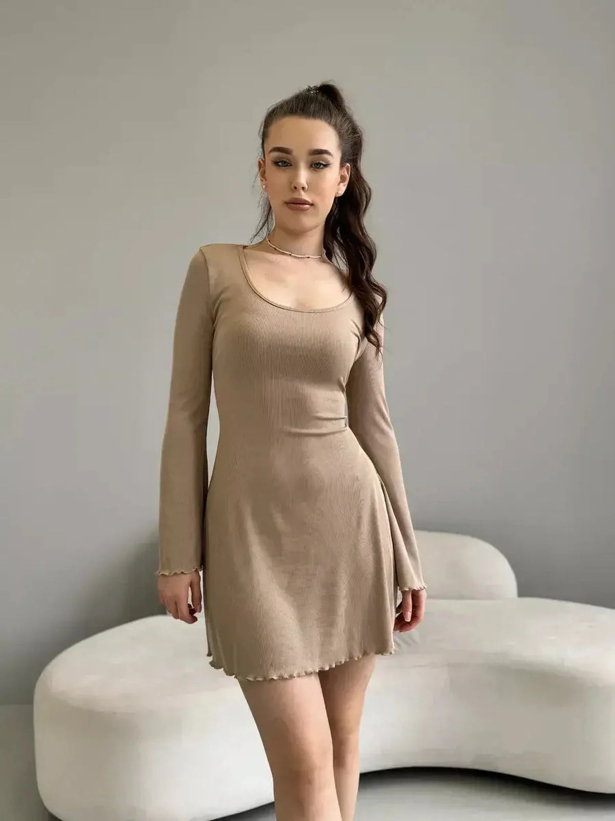 Model wearing Sahara Glow neutral-tone mini dress, featuring long sleeves, flared cuffs, and a squared neckline.