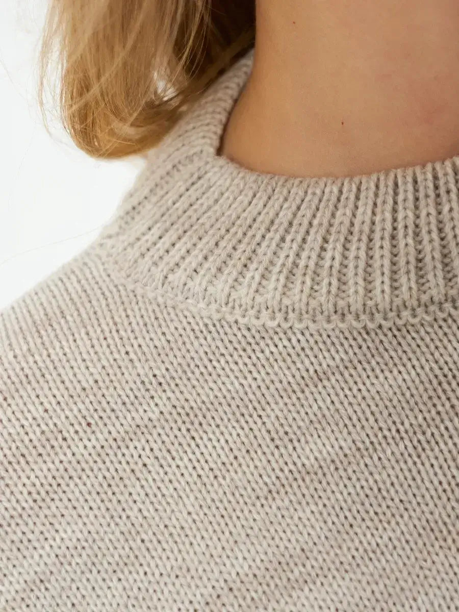 Close-up of the collar of the Sand Sweater by Lauven, showcasing its soft light beige knit texture.