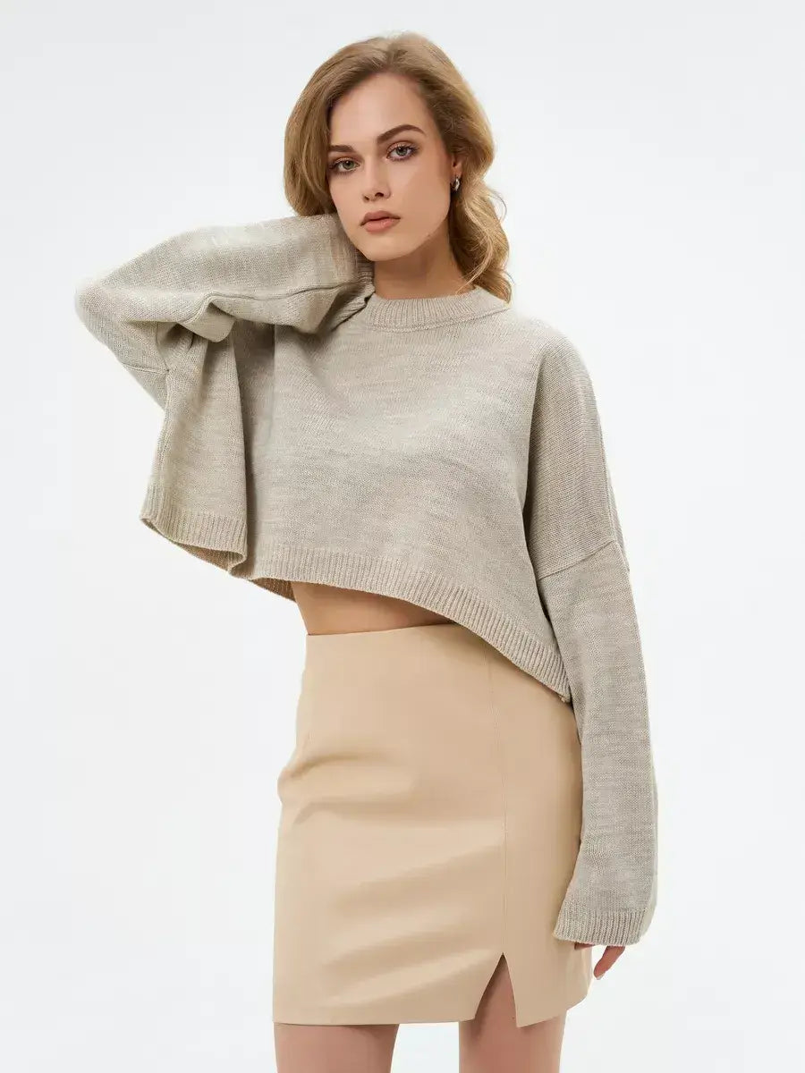 Model showcasing the Sand Sweater by Lauven, a cropped oversized knit in light beige, paired with a beige skirt.