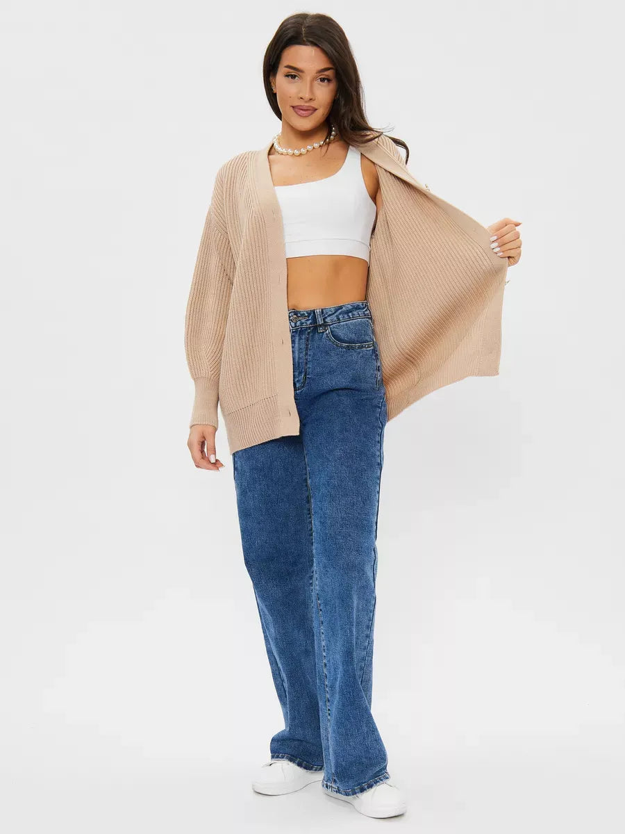 Stylish woman wearing a Sandstone Cardigan from Lauven, oversized knitwear in beige, paired with wide-leg jeans.