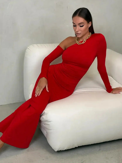 One-shoulder red maxi dress on a model, showcasing elegant draping and a chic silhouette in a modern setting.