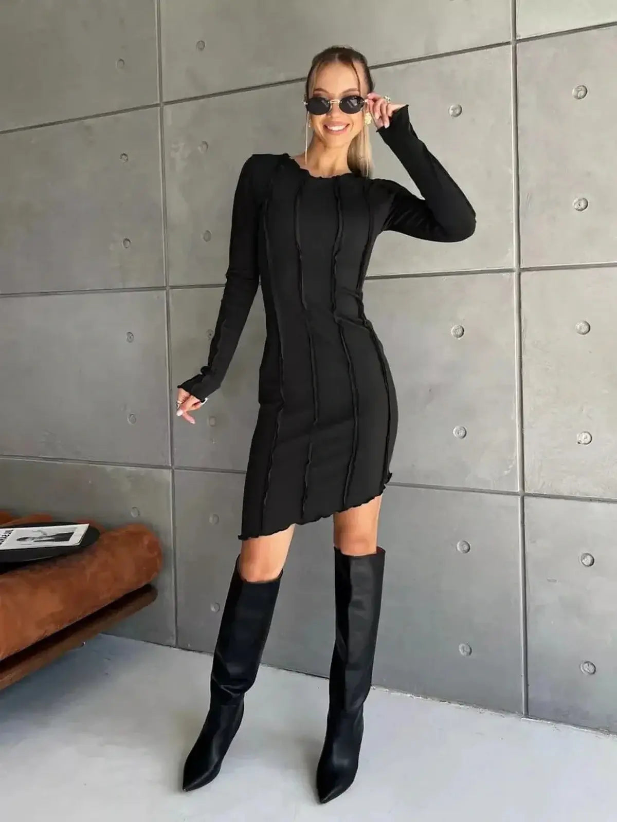 Model wearing a stylish black mini dress with long sleeves, perfect for parties and special occasions.