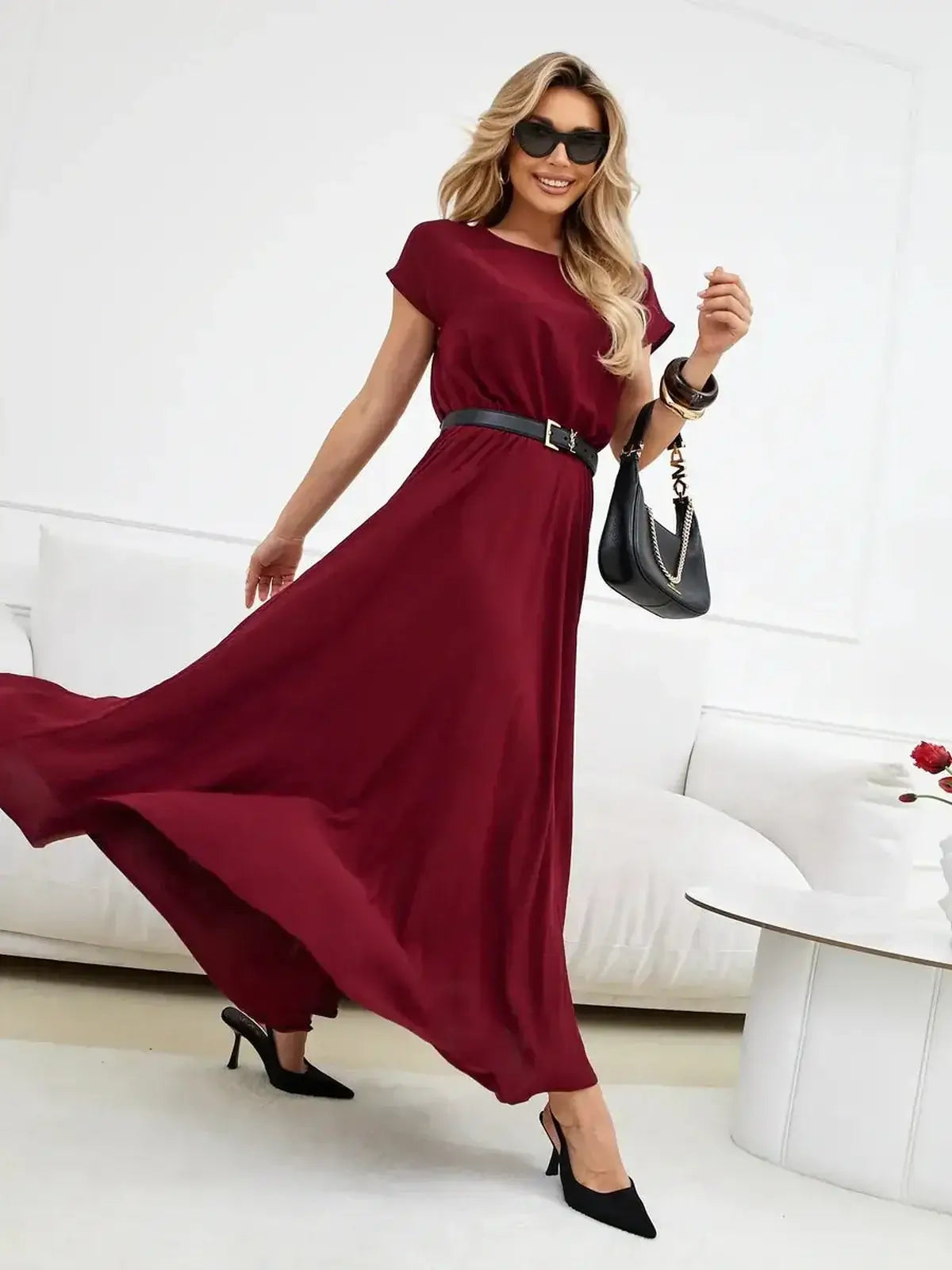 Woman in a burgundy maxi dress with a cinched waist, styled with a belt and heels, showcasing laid-back elegance.