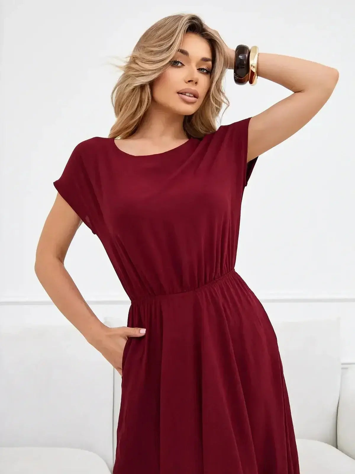 Model wearing the Sculpted Ease Maxi Dress in deep burgundy, showcasing its airy fit and cinched waist design.