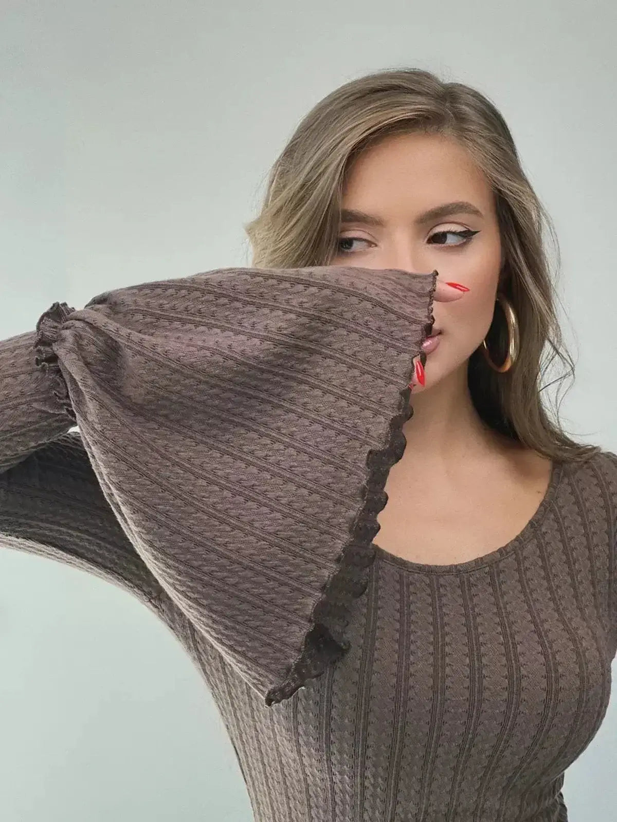 Model showcasing the Sculpted Grace Maxi Dress with flared sleeves and rich chocolate brown fabric.