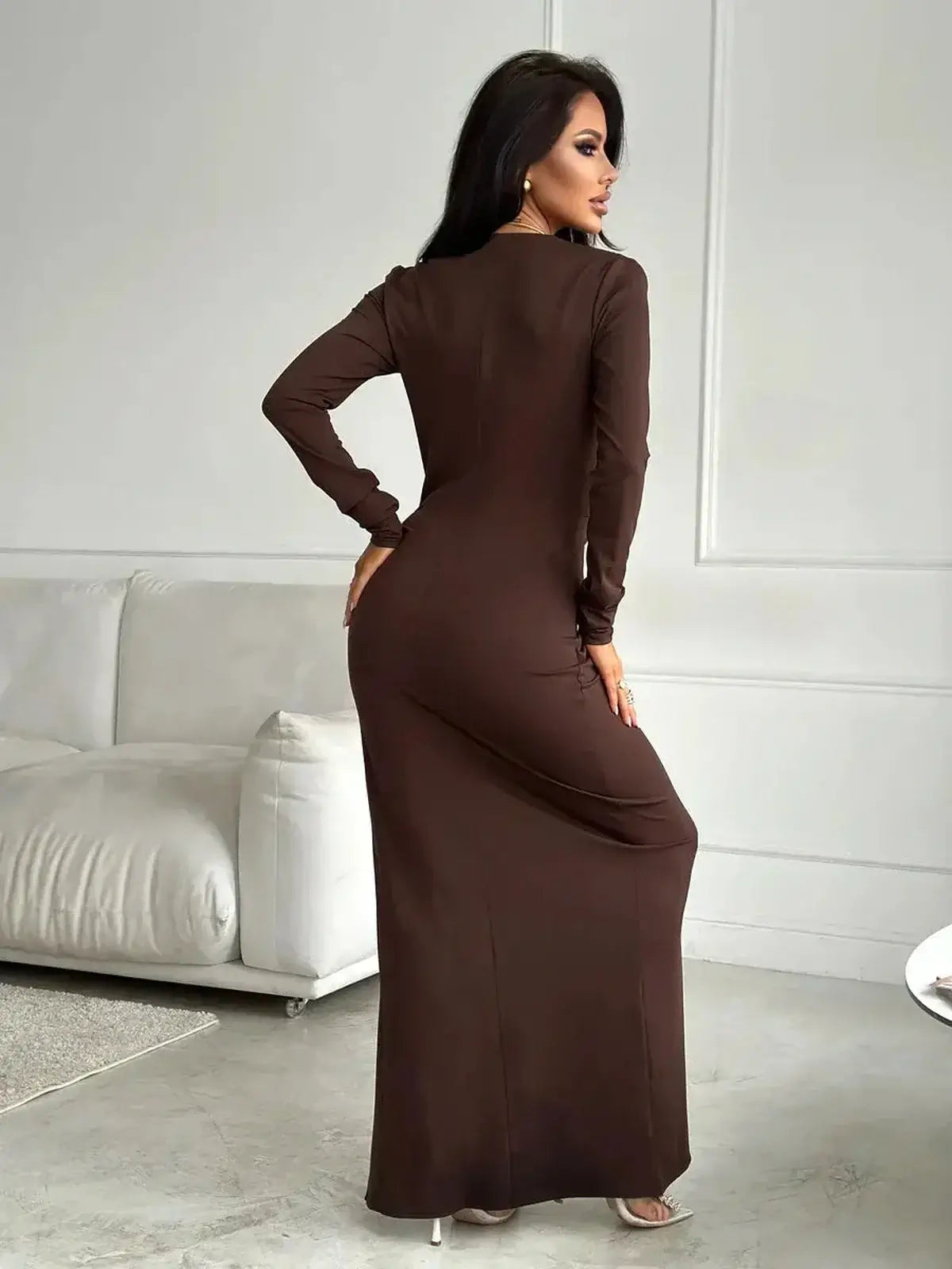 Elegant woman wearing a Sculpted Grace Maxi Dress in rich chocolate, showcasing a sleek silhouette and high slit from the back.
