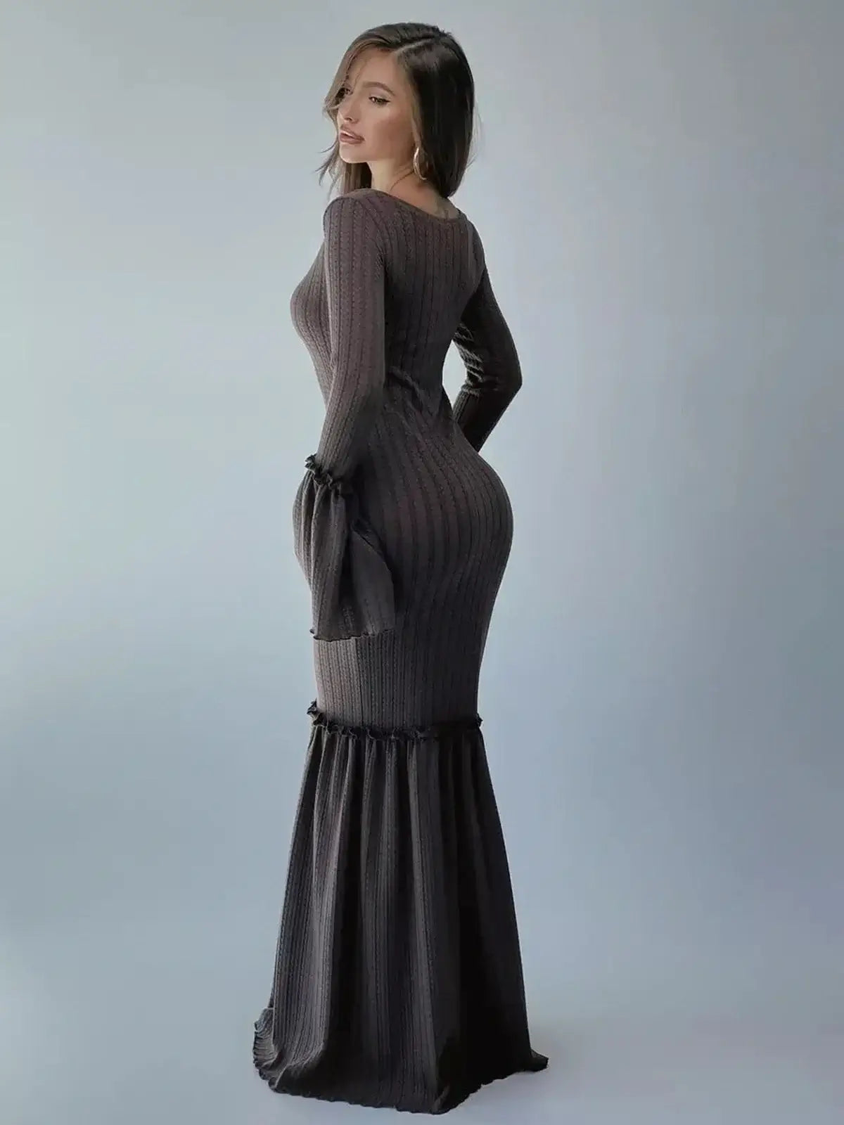 Model showcasing the Sculpted Grace Maxi Dress in chocolate brown, featuring fitted elegance and a dramatic flared hem.