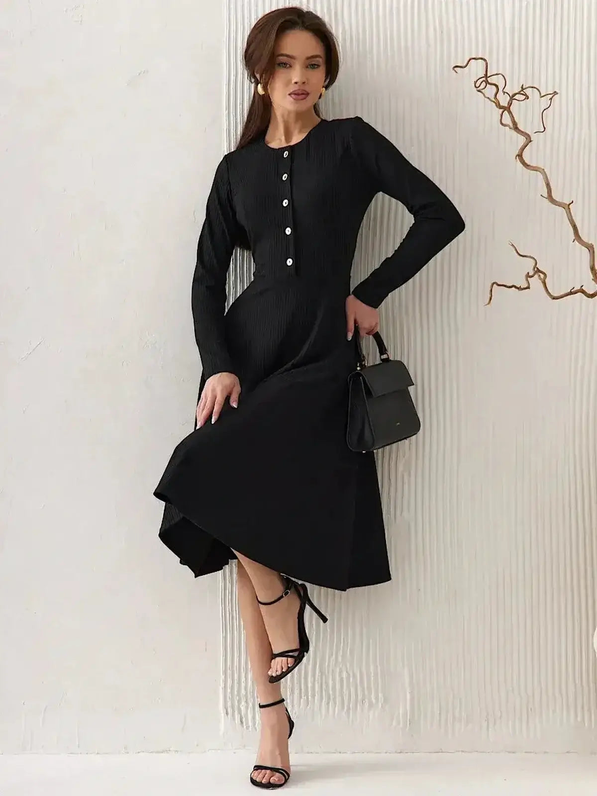 Model showcasing the Serene Grace Midi Dress by Lauven, featuring a black ribbed silhouette with decorative buttons.