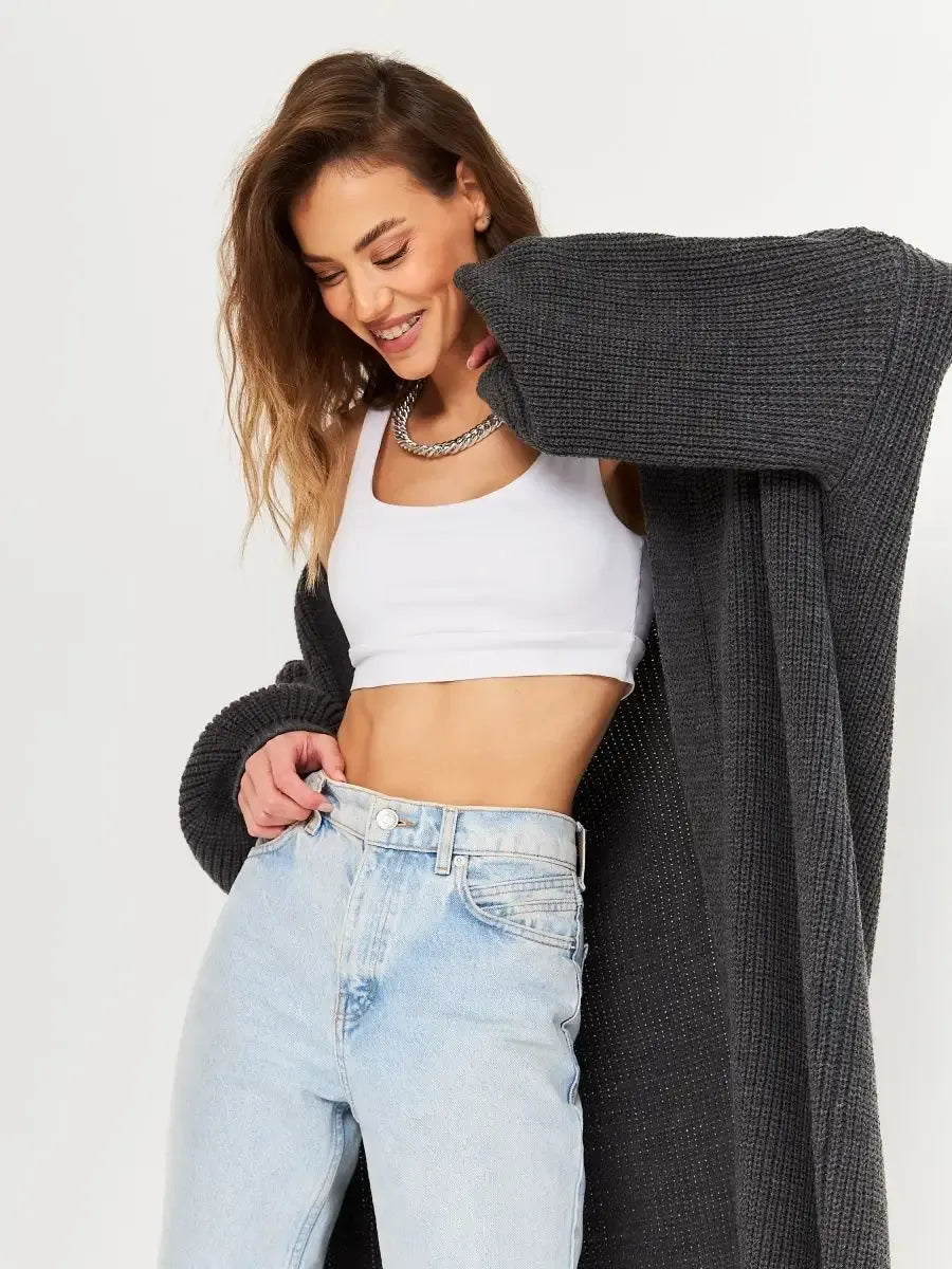 Woman wearing a Shadow Cardigan by Lauven, stylishly layered over a white crop top and light blue jeans.