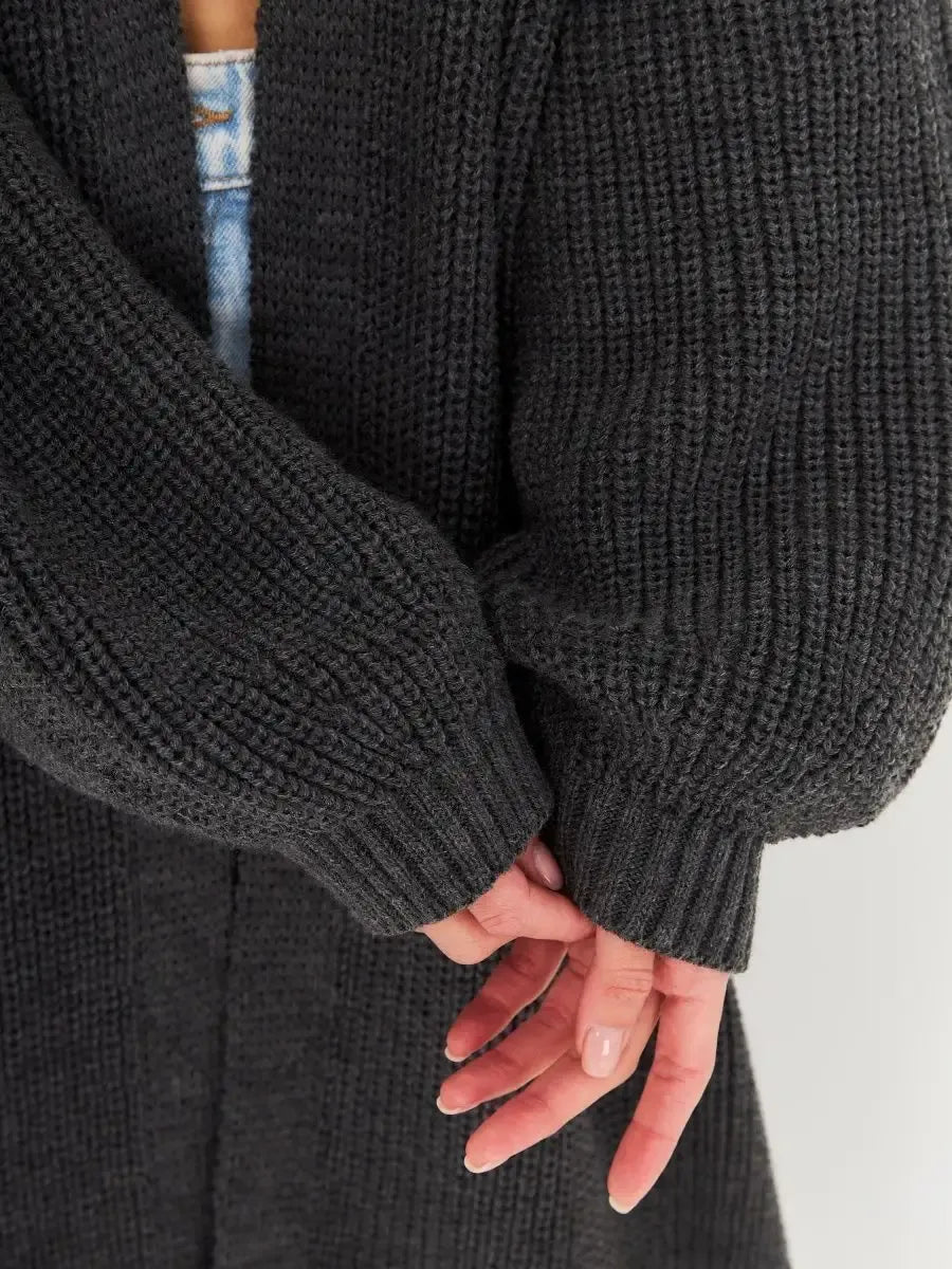 Close-up of Shadow Cardigan by Lauven, showcasing oversized knitwear and cozy fabric sleeves in deep gray.