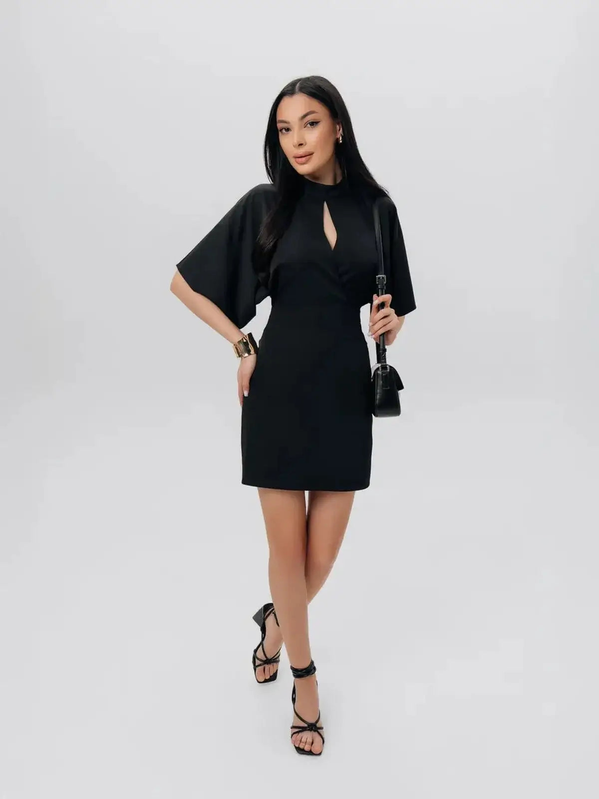 Model wearing the Shadow Grace black mini dress with sculpted silhouette and winged short sleeves.