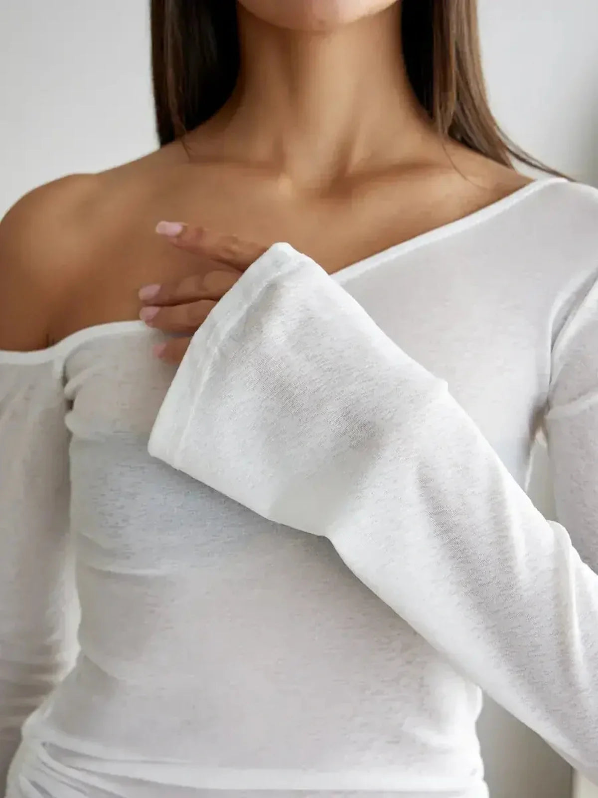 Close-up of a woman wearing an alluring white off-shoulder top, showcasing its lightweight fabric and stylish design.