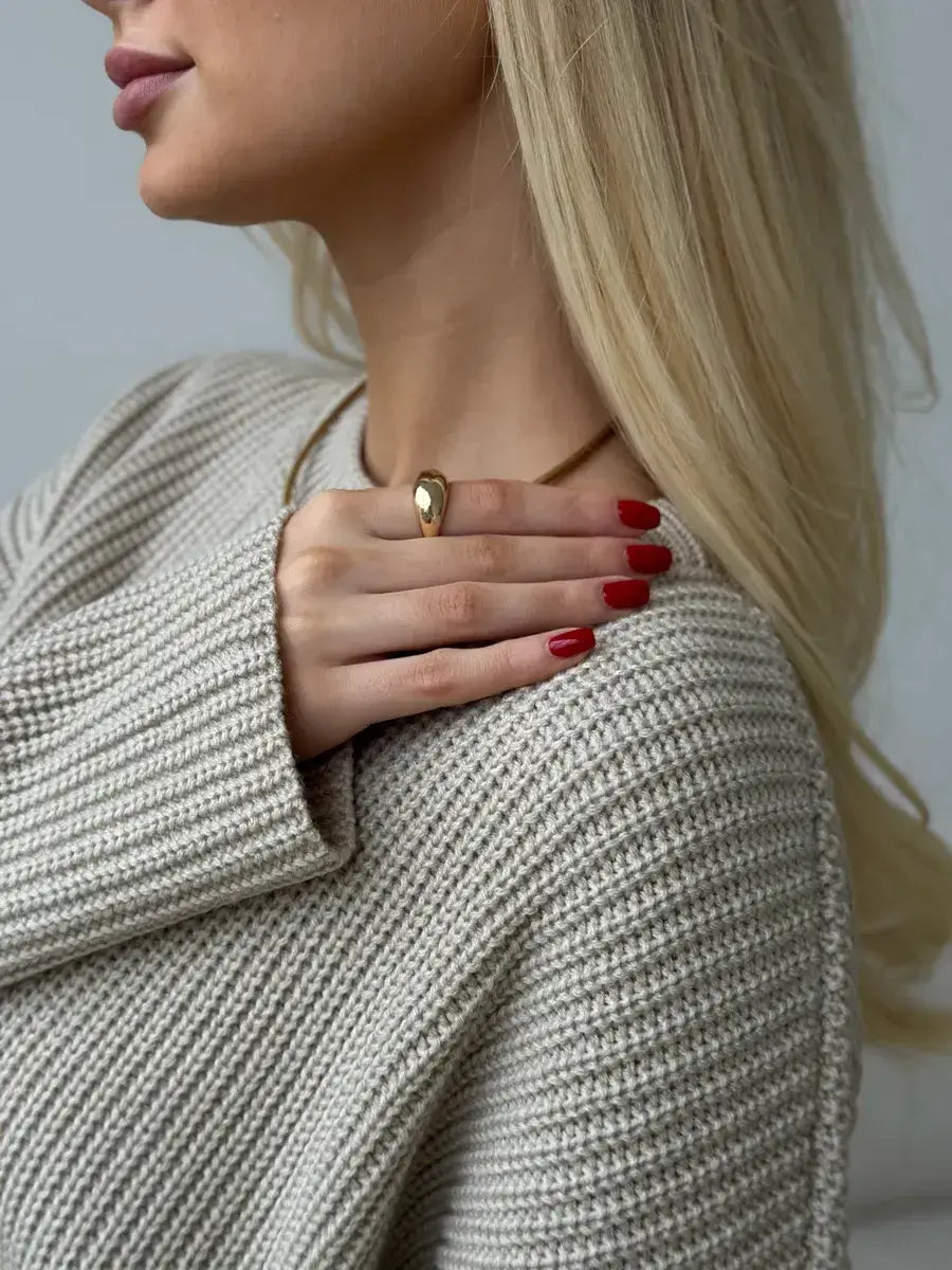 Model wearing the Sierra Sweater by Lauven, showcasing a stylish oversized beige knit and statement jewelry.