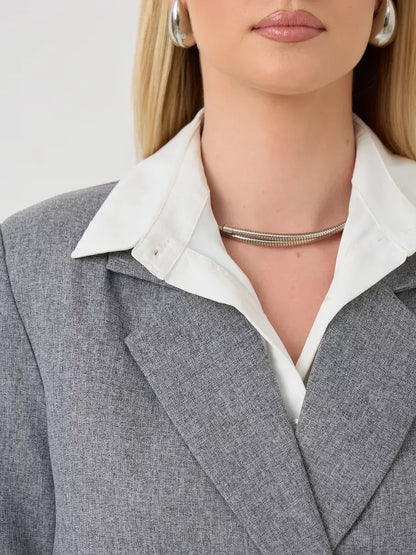 Close-up of the Silverstone Blazer by Lauven, featuring a gray tailored design with an oversized collar and elegant accessories.