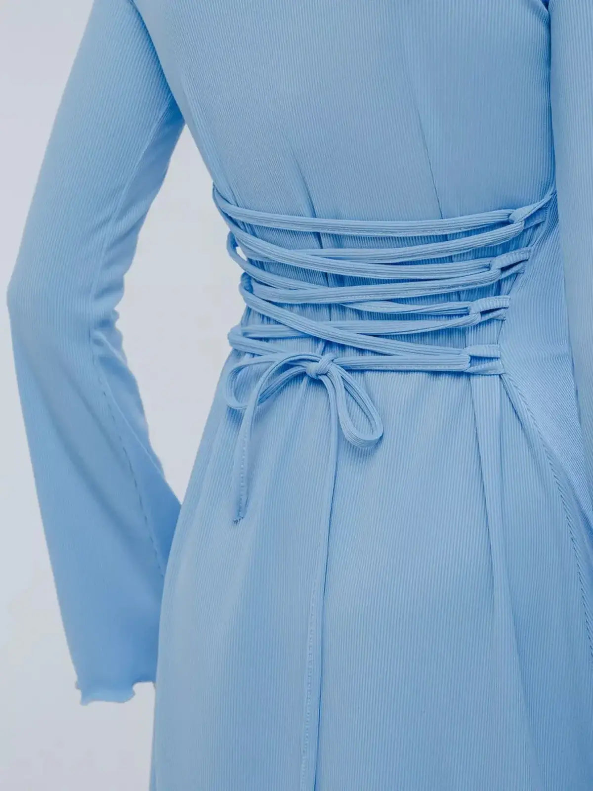 Close-up of a baby blue mini dress showcasing a signature lace-up back detail for a flattering fit.