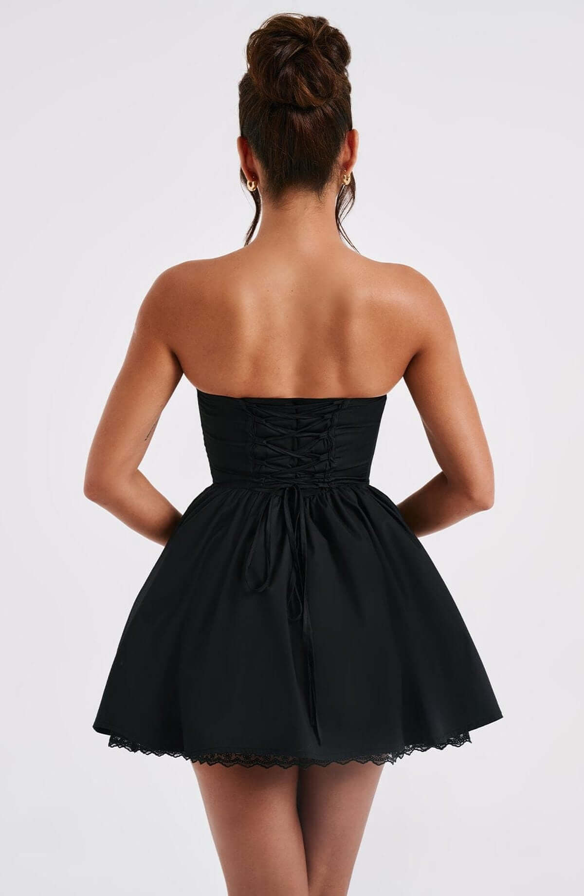 Back view of a strapless black mini dress with corset detailing and flared skirt, ideal for cocktail or party occasions.