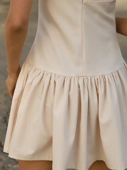 Back view of a soft beige mini dress with a flared skirt, perfect for summer occasions and formal events.