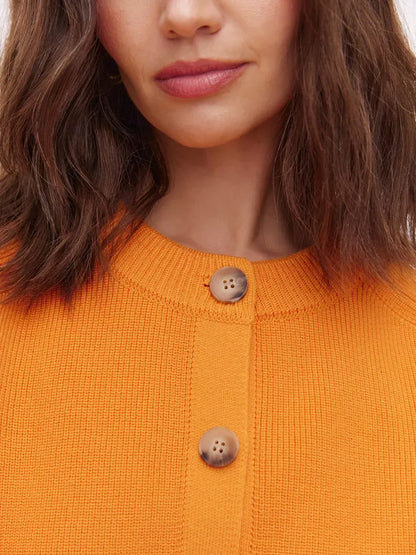 Close-up of the Solana Cardigan by Lauven, featuring a vibrant orange knit and button-up details.