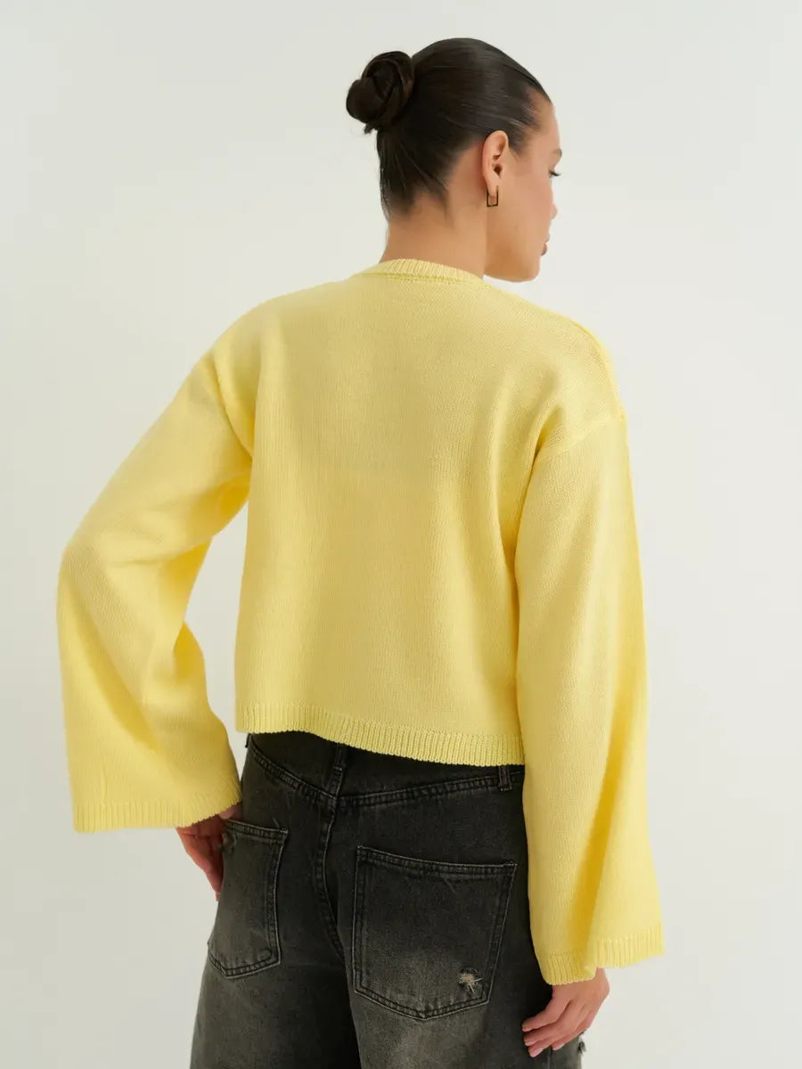 Woman wearing Solara Cardigan by Lauven, a lightweight cropped yellow knit with tie-front detailing.