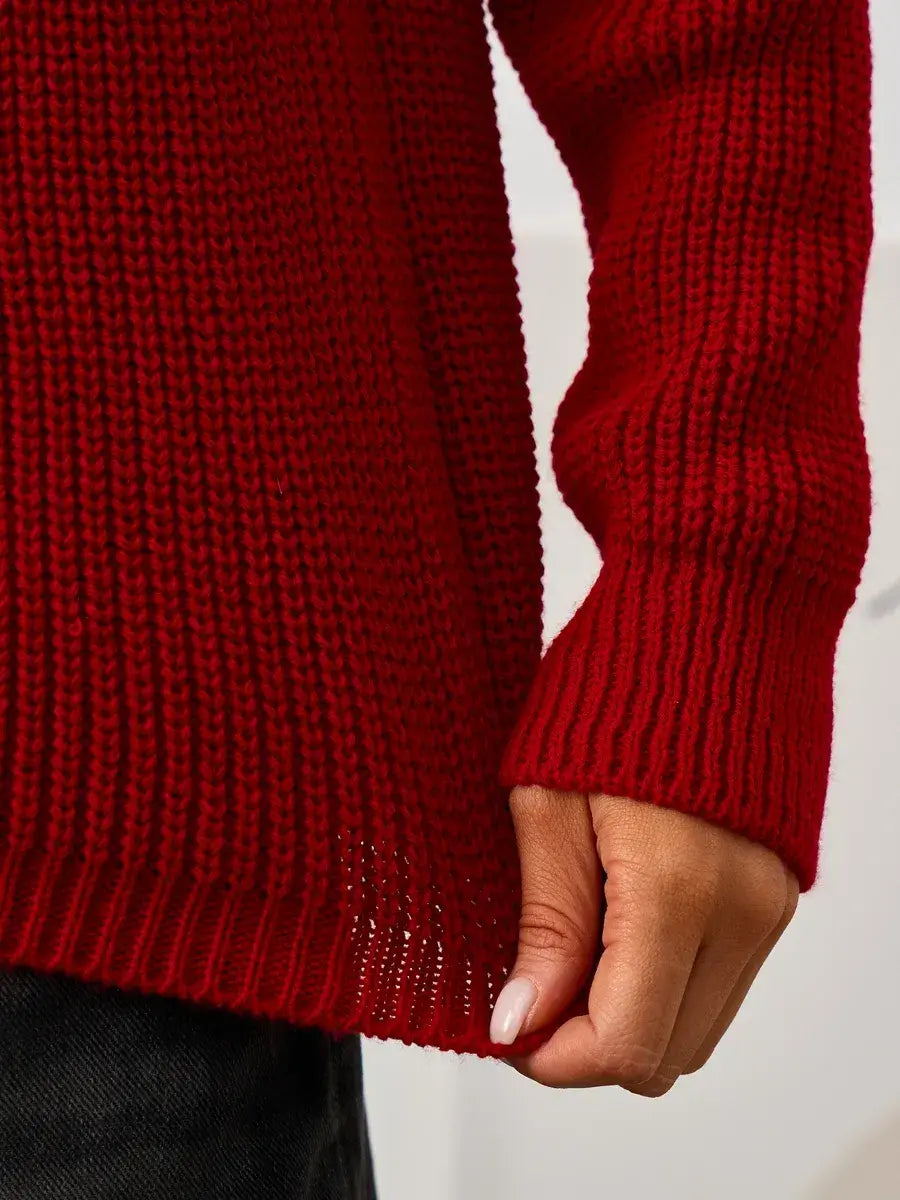 Detail shot of woman holding the hem of the Solara Sweater by Lauven, showcasing its rich red knit texture.