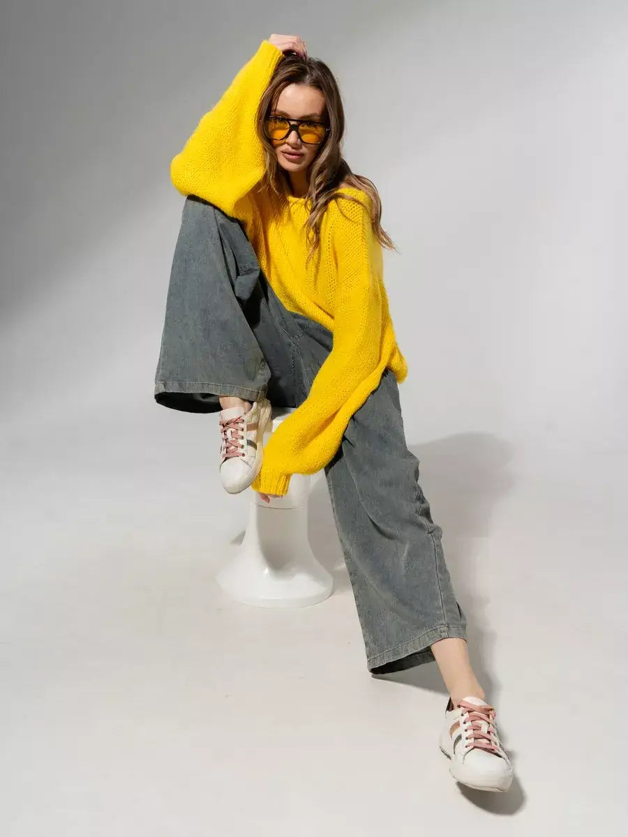 Model wearing Solara Sweater in bright yellow by Lauven, styled with wide-leg jeans and sneakers.