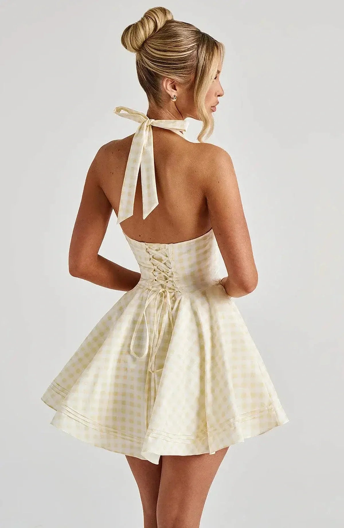 Back view of the Sunny Mini Dress in yellow gingham, showcasing halter neckline and playful skirt silhouette.