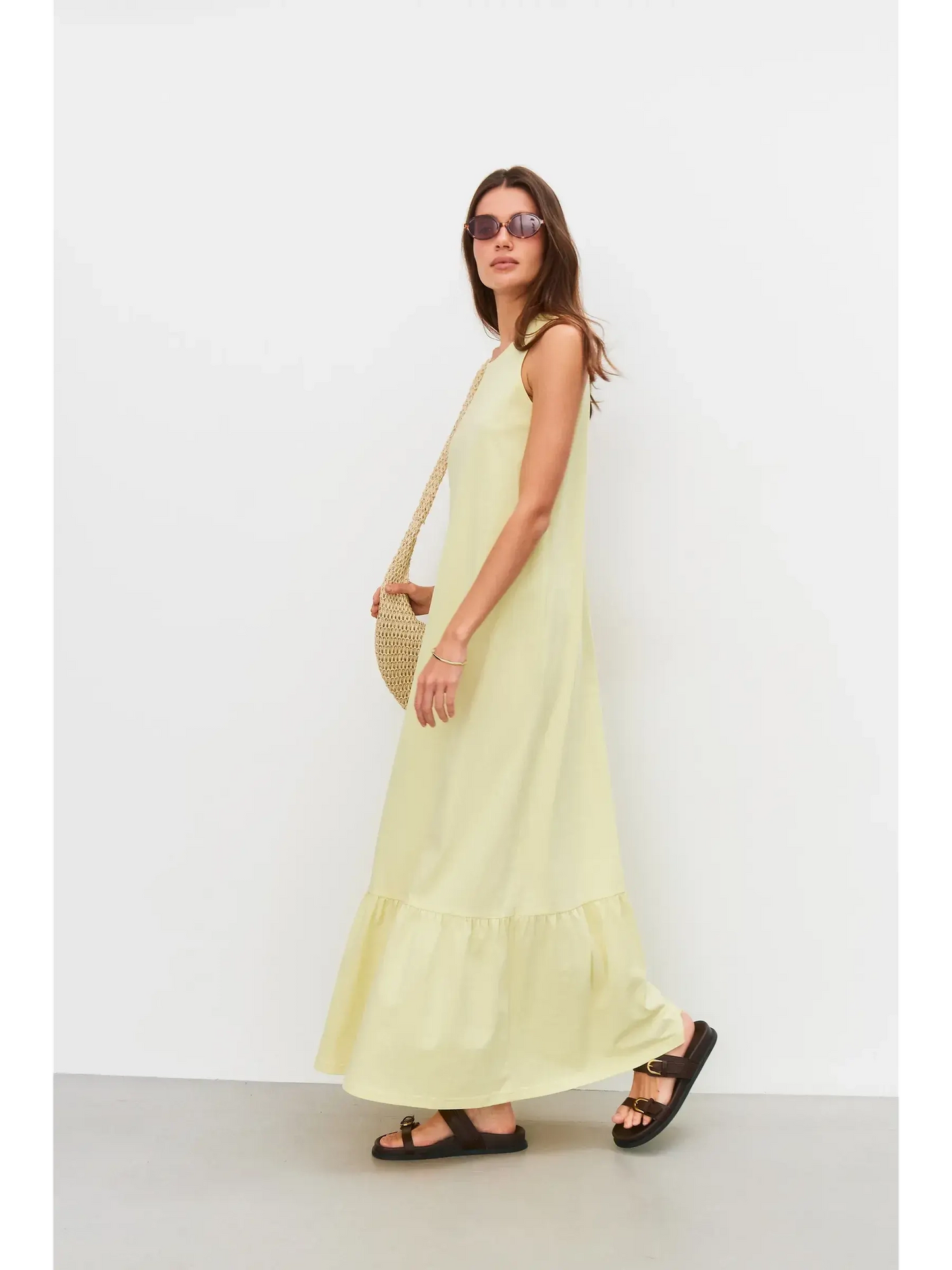 Model wearing a sleeveless light lemon Sunrise Maxi Dress with flounce hem, styled for summer outings.
