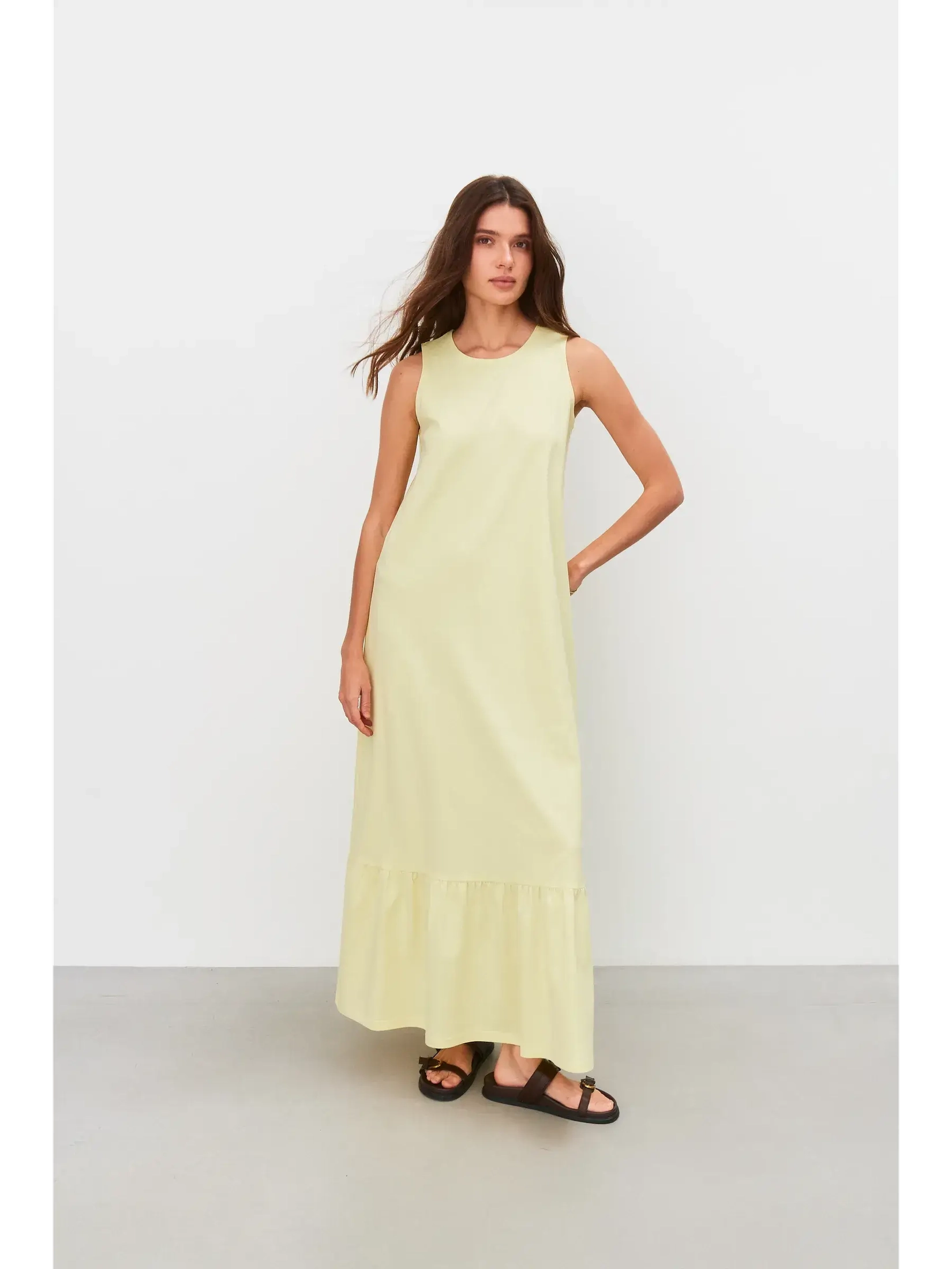 Model wearing a sleeveless Sunrise Maxi Dress in light lemon, showcasing a relaxed fit and gathered hem for summer elegance.