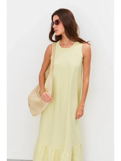 Model wearing a sleeveless light lemon Sunrise Maxi Dress, paired with sunglasses and a woven bag.